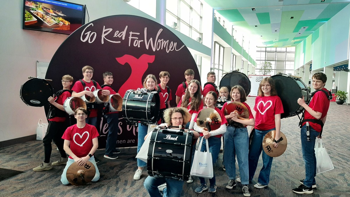 Band members standing in front of Red Cross event sign