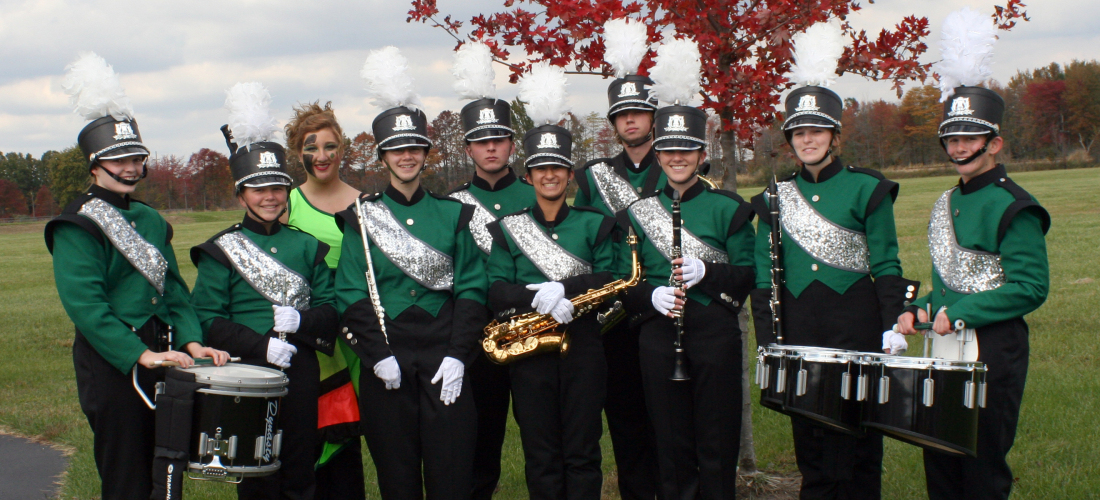 Marching band members in uniform with their instruments In front of Music Hall