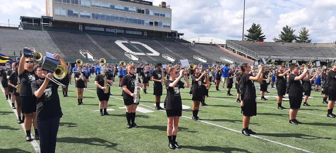 Marching band performing on a football field during OU Band Day